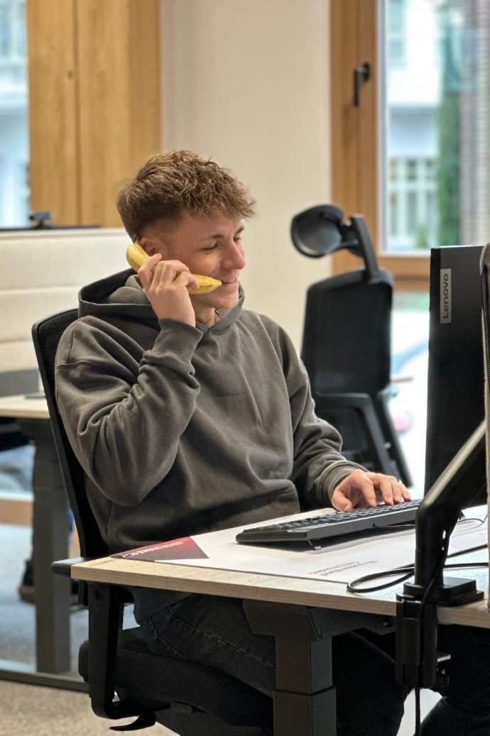Mann am Schreibtisch mit einer Banane als Telefon 